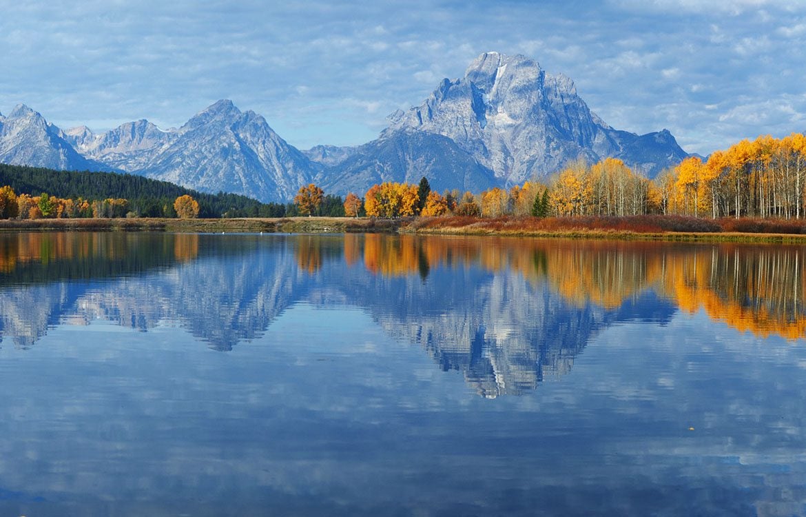 Yellowstone. View of mountains and autumnal forest across a clear lake